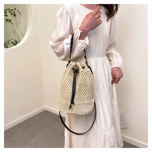 Gros plan d'un sac seau tissé beige avec cordon de serrage noir et bandoulière