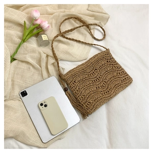 Detail of hand-woven straw shoulder bag with elegant fringe tassel and wavy texture