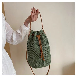 Détail du sac seau tressé vert avec cordon en cuir marron et finitions dorées chic