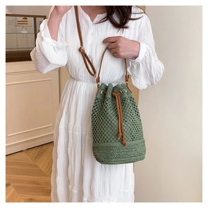 Détail du sac seau tressé vert avec cordon en cuir et texture en maille sur le mannequin