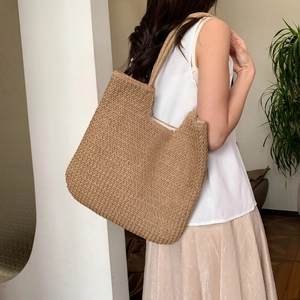 Detail of hand-woven brown straw shoulder bag showing dense texture and large capacity