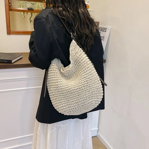 Minimalist woven hobo bag in creamy white with brown leather strap, shown on a shoulder