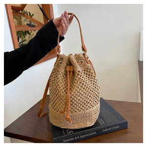 Détail du sac seau en paille tressée avec cordon de serrage et poignée en cuir marron