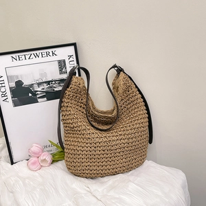 Minimalist straw woven tote bag with brown leather straps shown in a lifestyle scene
