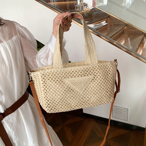 Beige woven straw tote bag with shoulder strap shown by a model in casual style