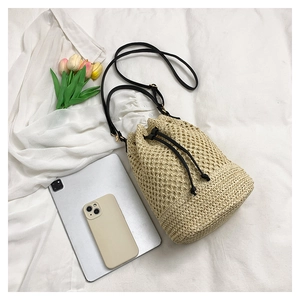 Détail d'un sac seau tissé beige avec maille losange ajourée et fermeture à cordon noir