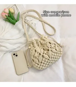 Detailed size comparison of a cream crochet bucket bag with a phone on soft fabric