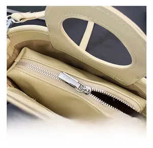 Close-up of internal zipper compartment and silver metal hardware of cream shell bag