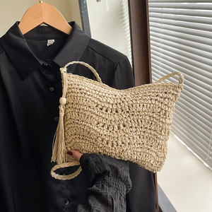 Minimalist beige woven straw crossbody bag with tassel detail and sleek shoulder strap