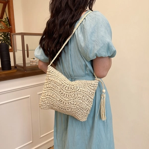 Chic beige woven crossbody bag with fringe tassels, worn by a model in a summer dress