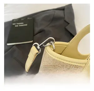 Detail showing silver metal hooks and beige canvas fabric with leather trim on bag
