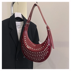 Detailed view of burgundy crescent bag with silver studs on adjustable shoulder strap
