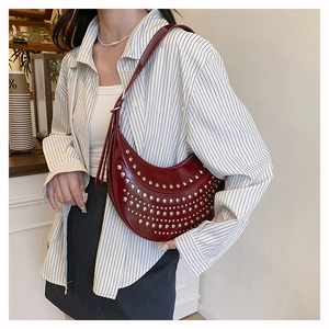 Detail of burgundy studded hobo bag featuring glossy leather and silver metal rivets