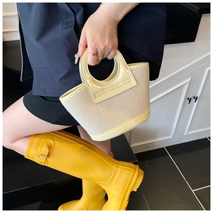 Detail view of cream woven shell bag featuring leather trim and circular cutout handle