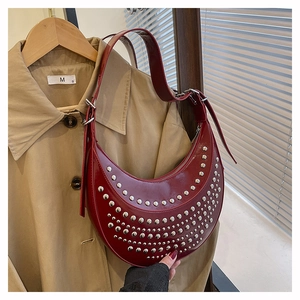 Close-up of deep red crescent hobo bag with silver rivets and glossy finish