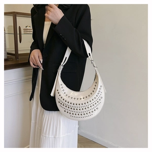 Close-up of white crescent hobo bag with silver studs and adjustable leather strap