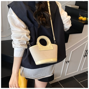 Chic beige woven mini shell bag with circular handle shown on model in casual setting
