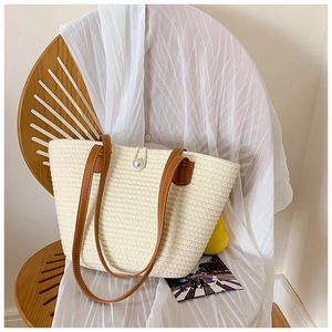 Minimalist cream woven tote bag with brown leather handles and a large pearl clasp detail