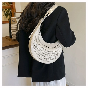 Detail shot of white leather crescent bag with silver rivets and sleek shoulder strap