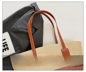 Detail of straw tote bag showing contrast leather handles and high-quality woven texture