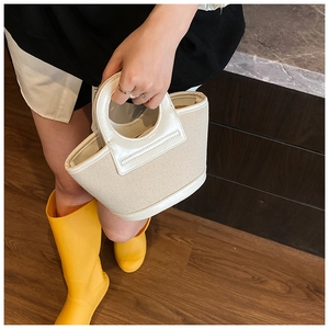 Detail of mini canvas bucket bag with beige fabric and white patent leather trim