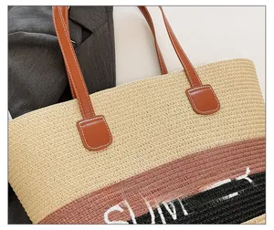 Detail of straw tote bag showing Summer embroidery and premium leather handle stitching