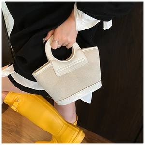 Detail of cream woven shell tote bag with circular handle in a minimalist style