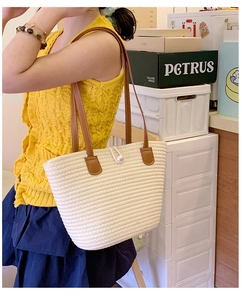 Detail of woven tote bag featuring a large pearl clasp and brown leather handles