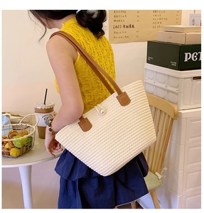 Close-up of cream woven tote bag with horizontal texture and elegant pearl magnetic clasp