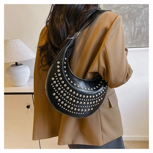 Detail of black crescent shoulder bag with silver studs on a matte leather surface