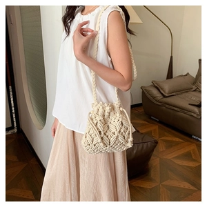 Handwoven cream bucket bag with diamond texture worn by a model in a casual setting