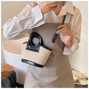 Detail of a mini bucket bag featuring a circular handle and contrast stitching texture