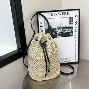 Sac seau en paille tressée beige avec lanières en cuir noir et cordon de serrage