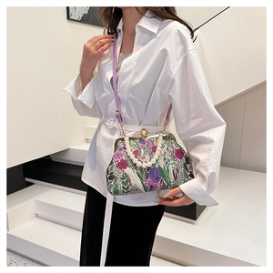 Detail of floral tapestry handbag with pearl handle and purple strap on minimal background