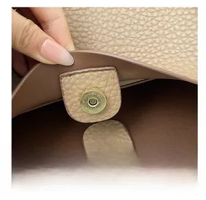 Detail shot of the magnetic snap closure and pebble grain leather on a brown tote bag