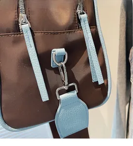 Detail of silver metal hardware and contrast stitching on the brown travel bag