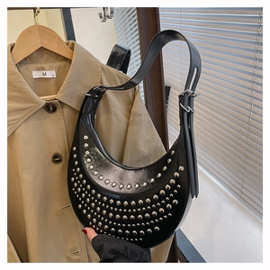 Detailed view of silver rivets on black glossy leather of the crescent shoulder bag
