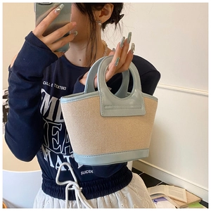 Detail of a beige woven shell bag with light blue patent leather handle for summer