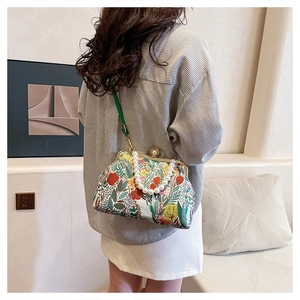 Detail of vintage floral evening bag with pearl handle and green leather shoulder strap