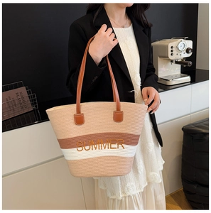 Detail of a large straw beach tote with summer embroidery and brown leather handles