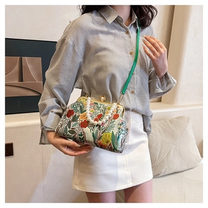 Floral crossbody bag detail with elegant pearl handle and vintage metal frame clasp