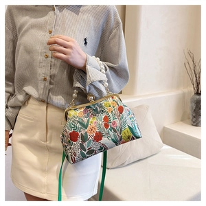 Detail of floral embroidery and elegant pearl handle on a vintage evening clutch bag