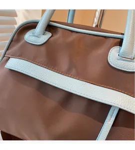Macro detail of brown nylon fabric and light blue lychee pattern leather stitching on travel bag