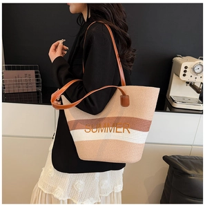 Close-up of the striped straw tote bag featuring orange SUMMER embroidery and leather handles