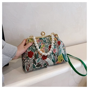 Detail of floral embroidery and elegant pearl handle on a retro evening crossbody bag