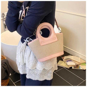 Side view of pink leather handle and woven beige shell bag worn by female model