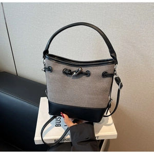 Close-up of contrast canvas bucket bag with leather handle and toggle drawstring detail