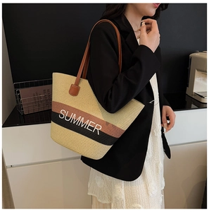 Detail of a large straw tote bag with color-block weave and SUMMER embroidery on shoulder
