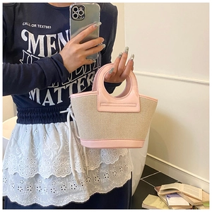 Detail of a small woven shell bag with pink leather trim held during an indoor selfie