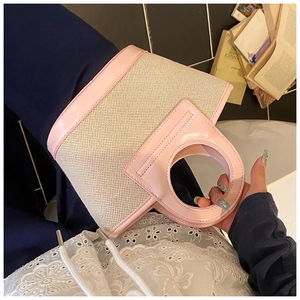 Detail of a pink and beige shell bag featuring a woven body and round cutout handle